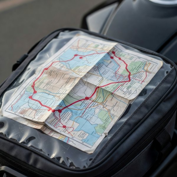 Paper road map folded in a clear tank bag window with fuel stops marked in red pen